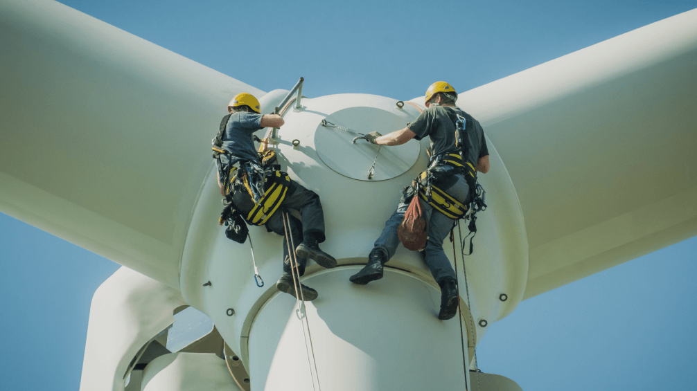 Two workers on a propeller at a wind farm