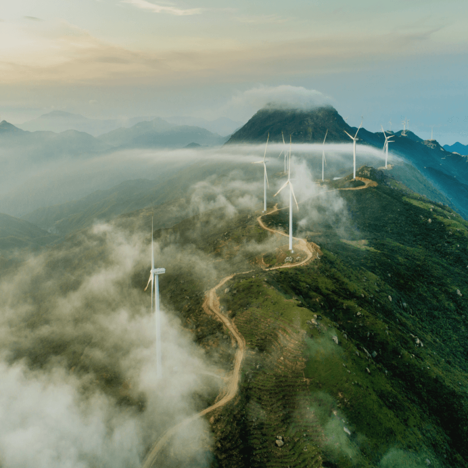 An aerial shot of wind turbines on a cloudy hillside.