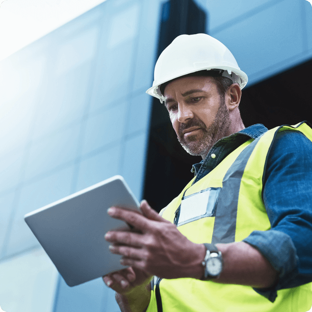 Industrial worker in front of a building on an iPad