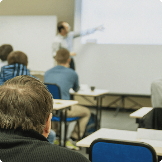 A classroom scene with the instructor pointing something from their presentation.