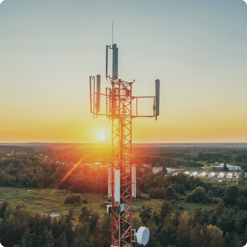 An image of a cell tower with the sun rising in the background