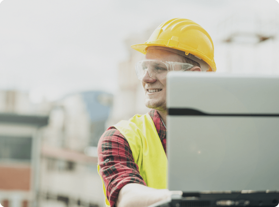 Image of a male industrial field worker with a hard hat and laptop