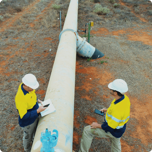 Two workers in front of a oil pipeline