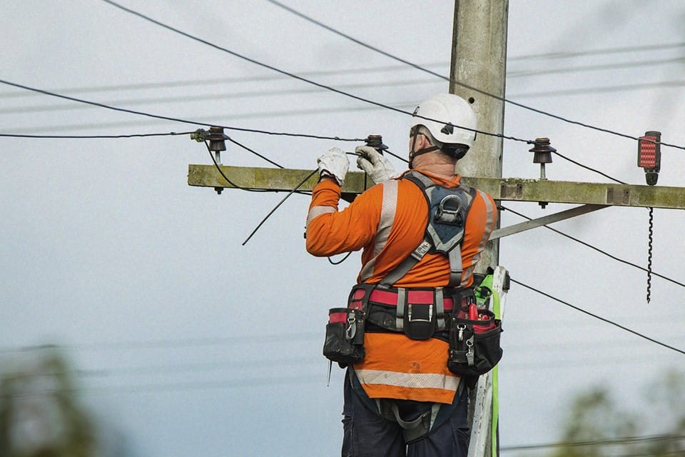 A municipal utilities worker repairs a telephone pole.